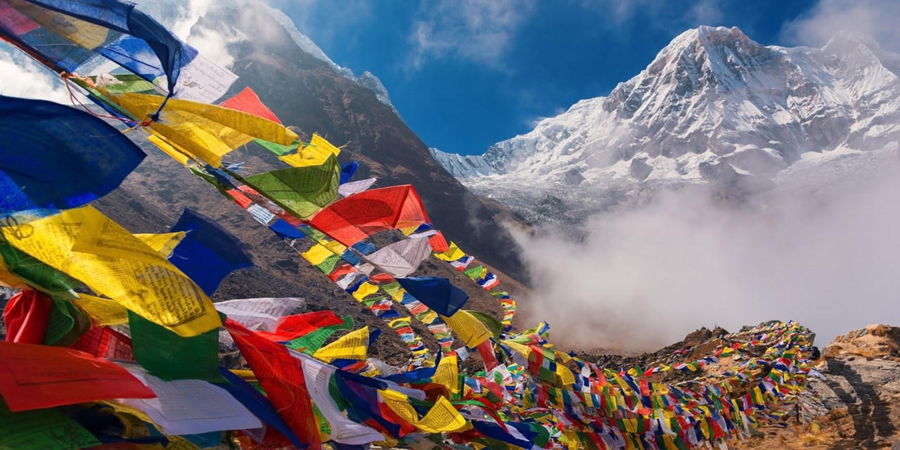 Tibetan prayer flags set against the massive, snow-capped backdrop of Mount Annapurna I