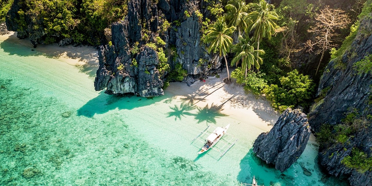 A boat rests in a secluded cove near El Nido's limestone cliffs