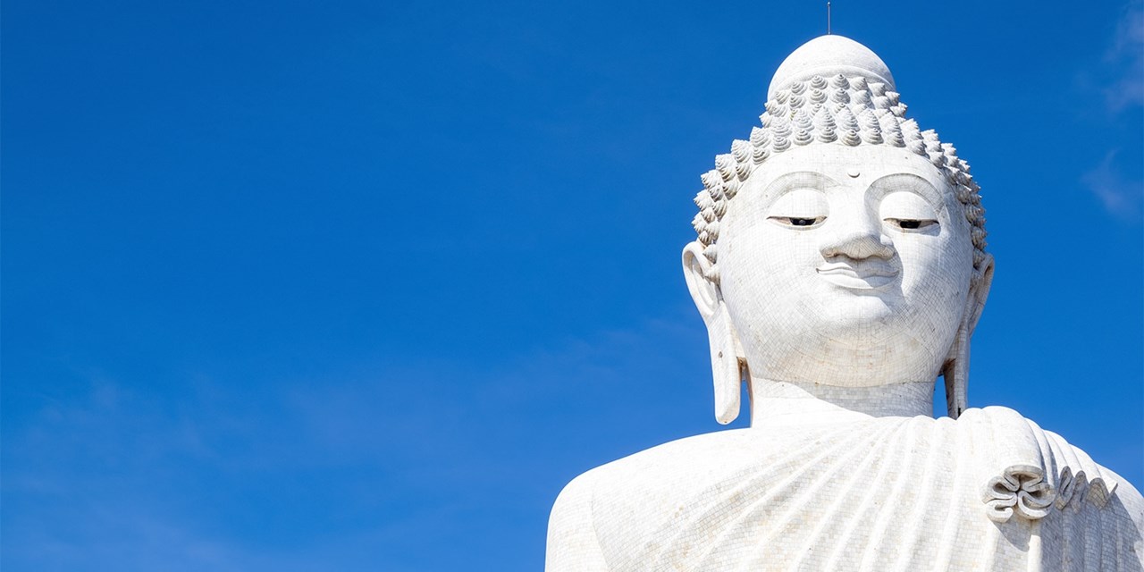 Marble Big Buddha statue stands against blue sky in Phuket
