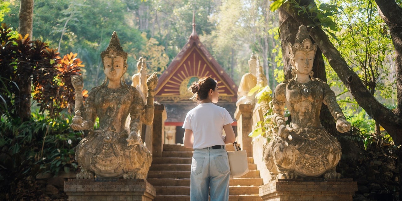 Visitor climbs stairway past deity statues at Chiang Mai temple