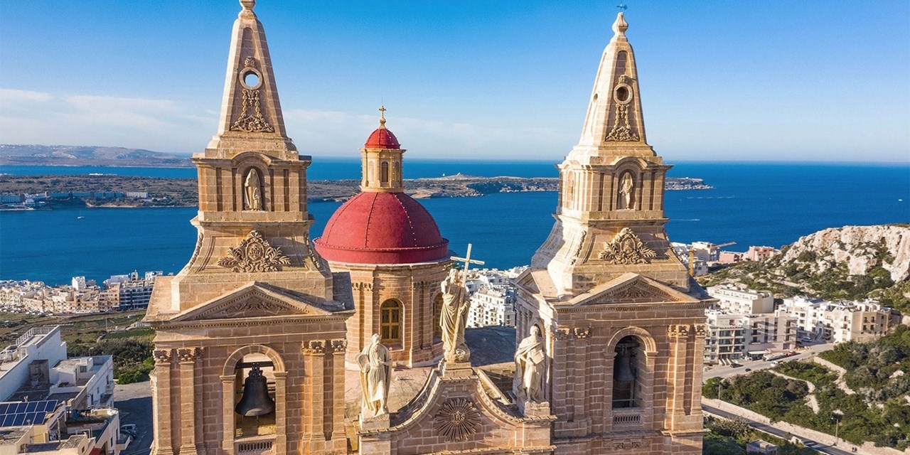 Ornate bell towers of Mellieha's parish church overlook the bay
